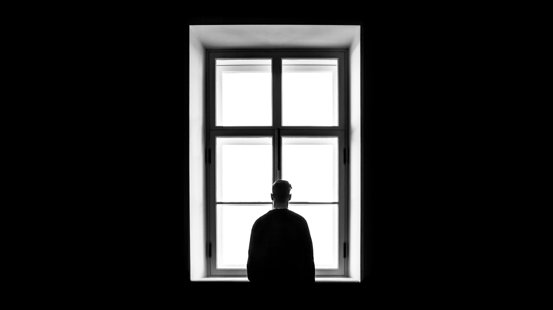 man looking out a window alone
